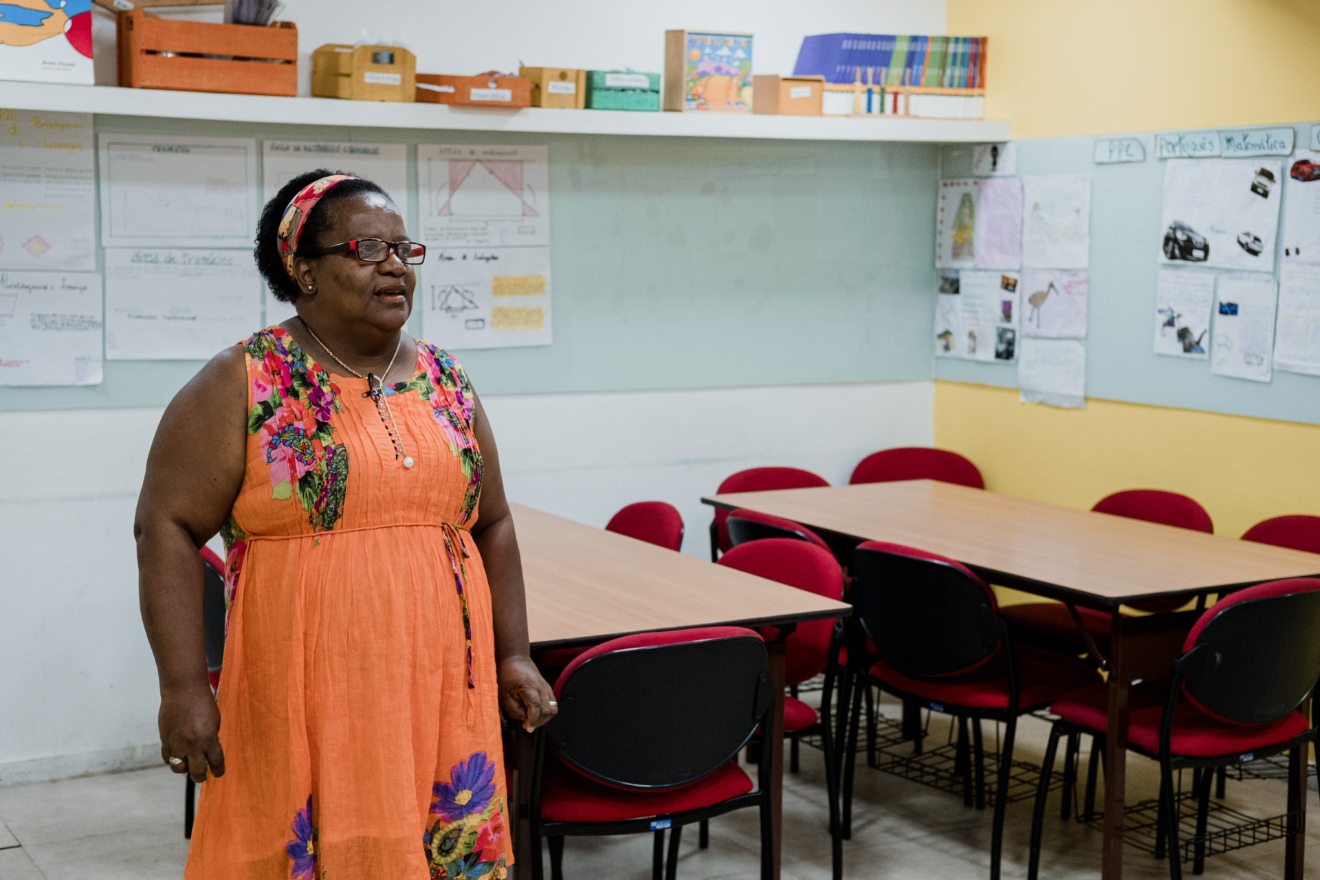 Uma mulher negra, de pé, no centro de uma sala de aula