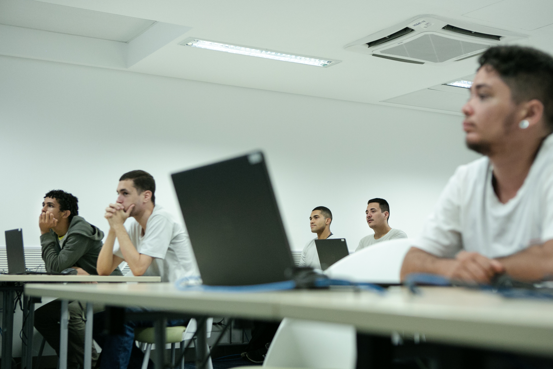 Jovens em uma sala de aula, com computadores sobre a mesa