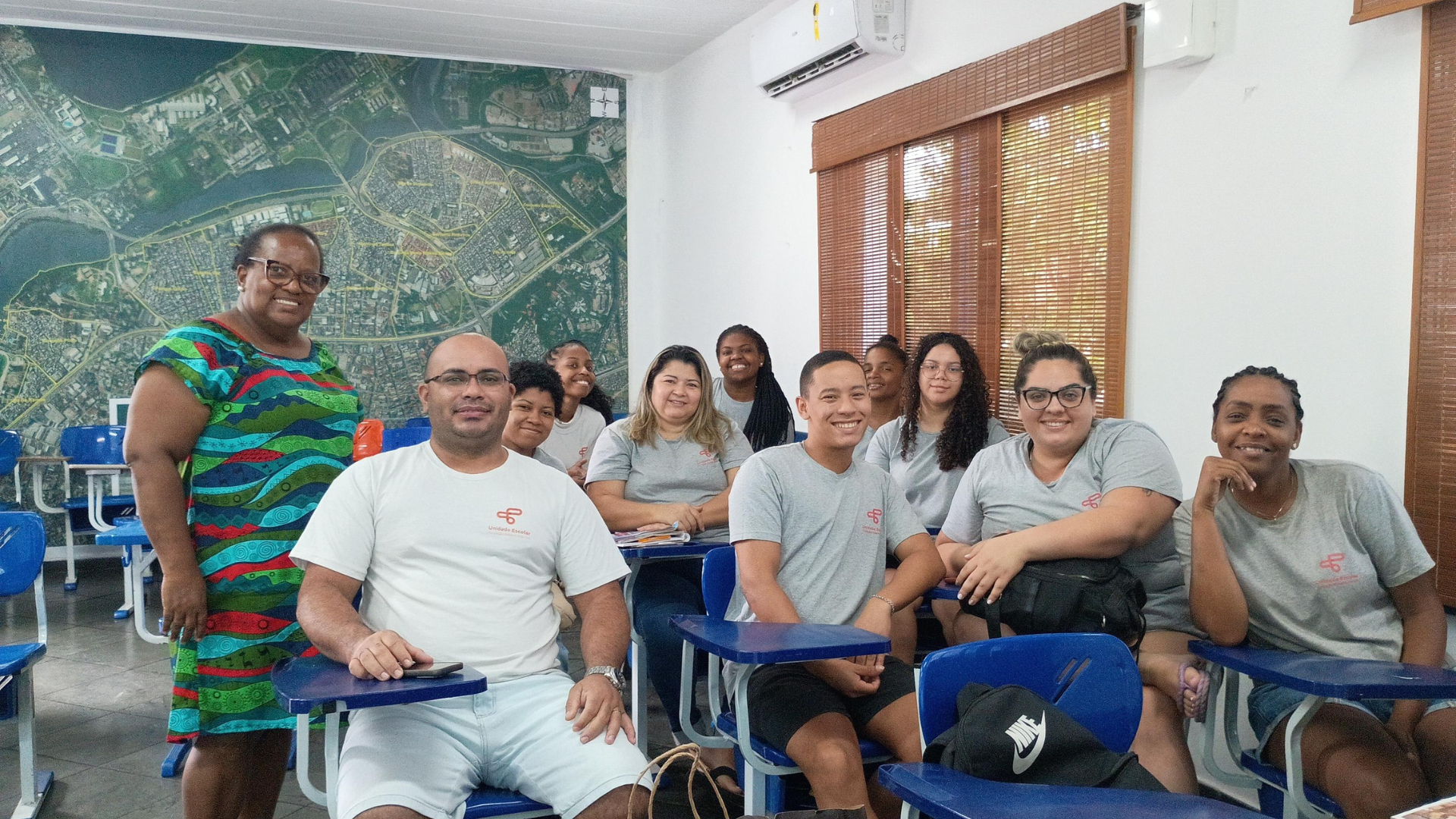 Uma mulher negra de pé ao lado de um grupo de estudantes sentados juntos,