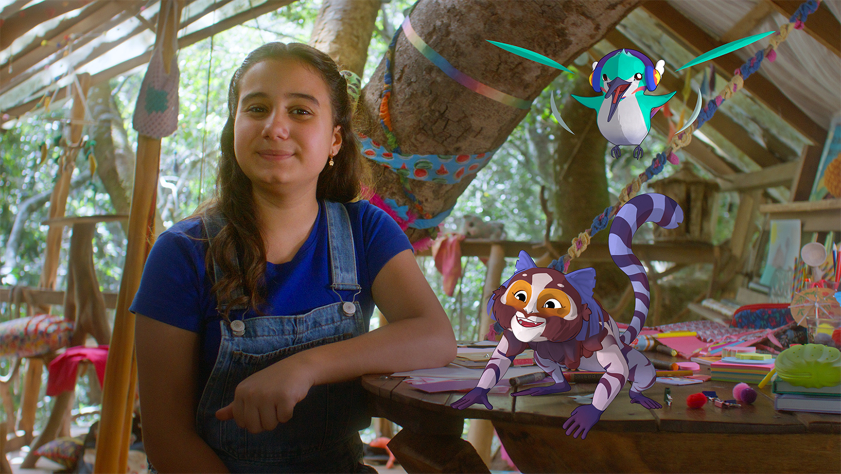 Imagem da série infantil Comer, Beber e Aprender. A foto mostra uma menina sentada e com o braço apoiado em uma mesa, e, ao seu lado direito, aparecem um macaco e um pássaro inseridos graficamente.