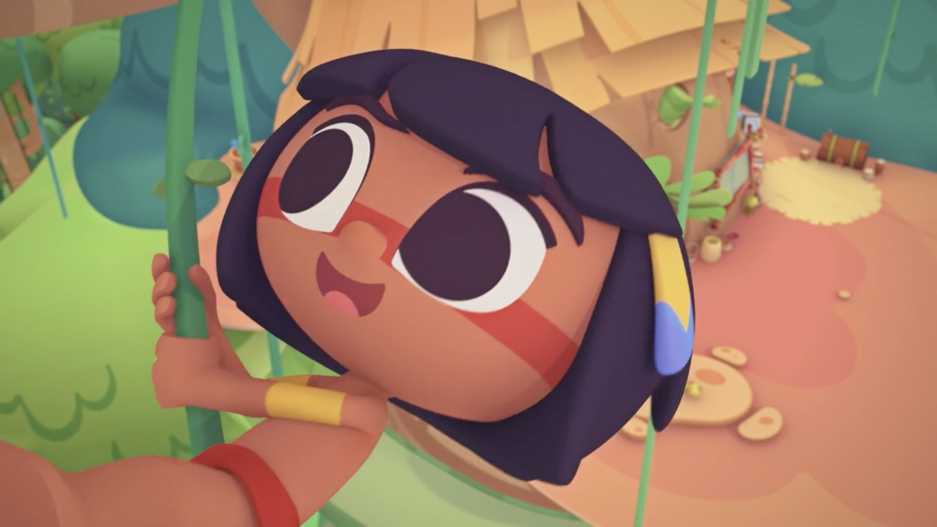 Imagem em animação 3D mostra uma criança indígena com pintura vermelha no rosto, grandes olhos expressivos e cabelos pretos. Ela segura uma corda ou cipó, sorrindo, em meio a um cenário de floresta estilizada com ocas e vegetação ao fundo.