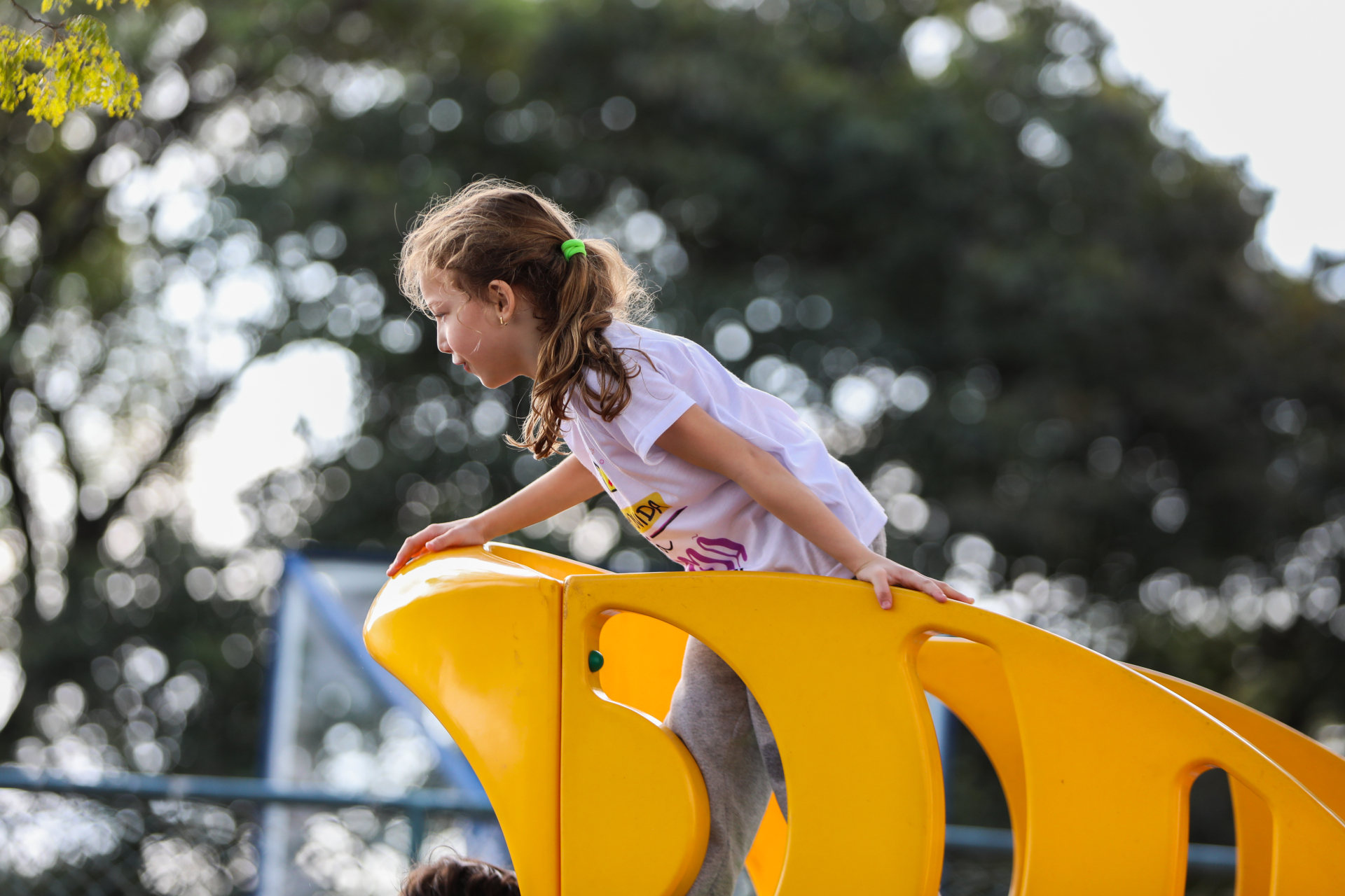 A imagem mostra uma menina brincando em um parquinho