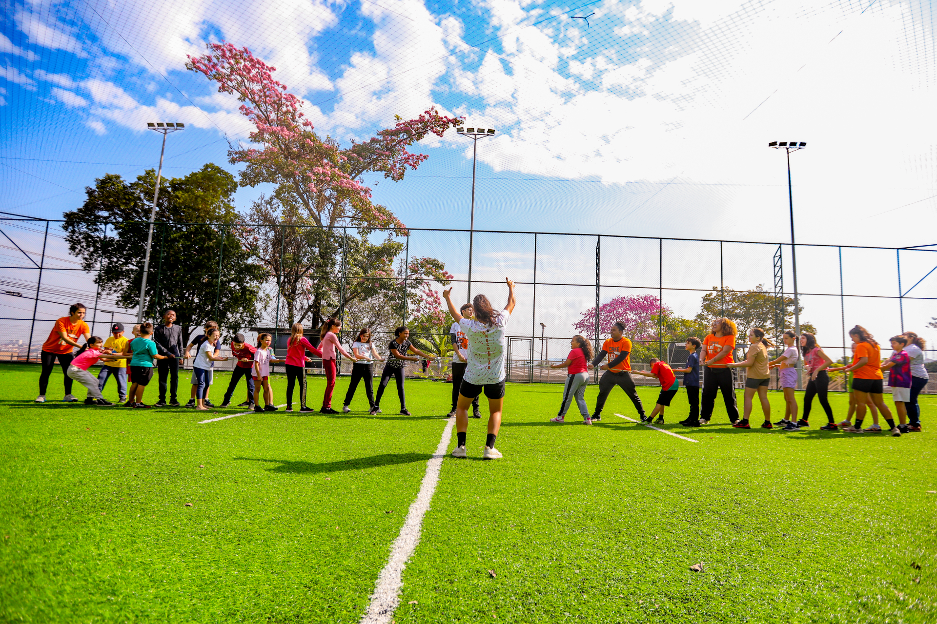 A foto mostra crianças fazendo um cabo de força em um campo de futebol