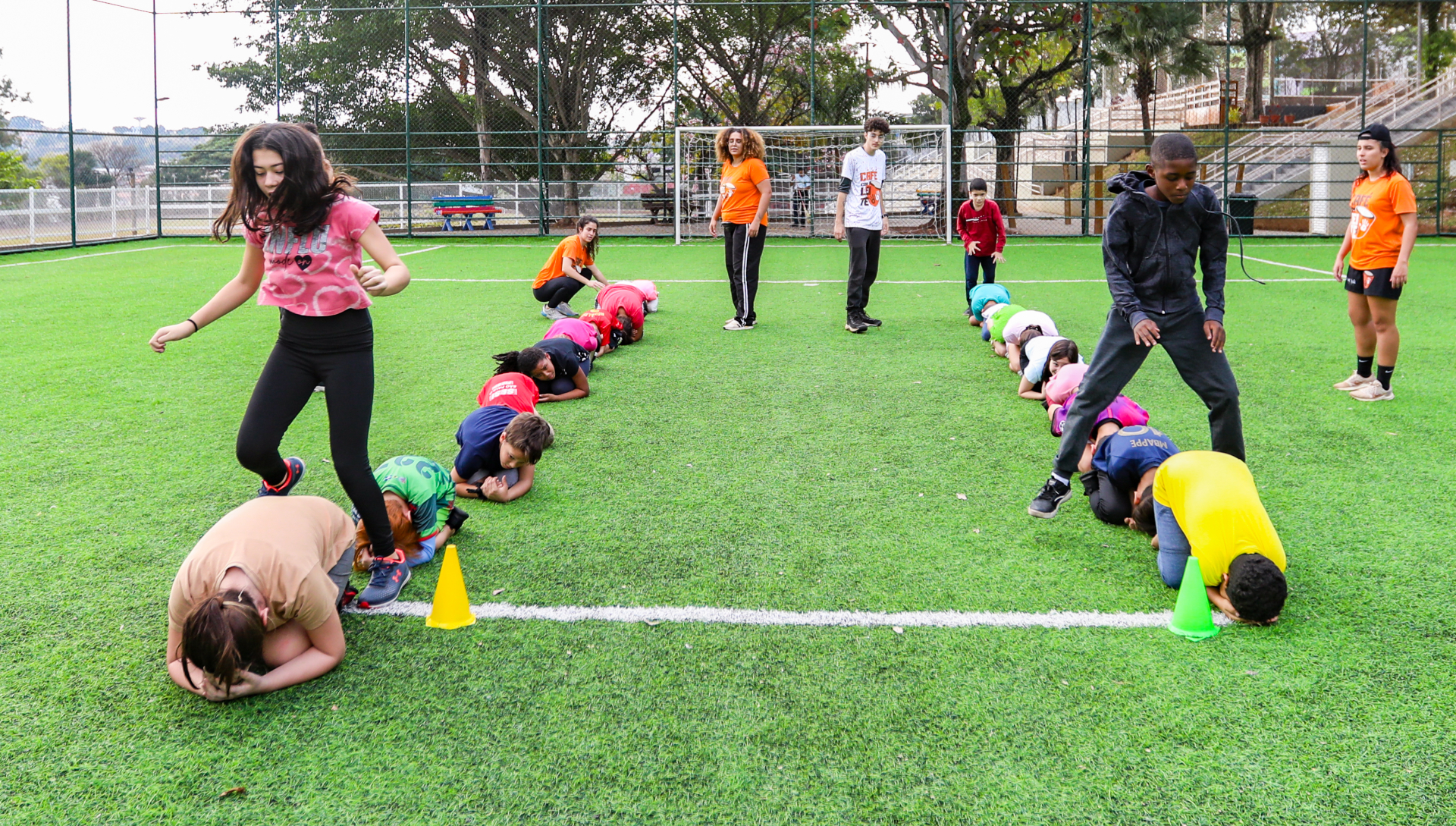 A foto mostra crianças brincando em um campo de futebol