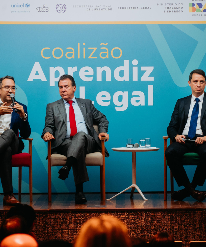Quatro homens sentados. Todos de terno.