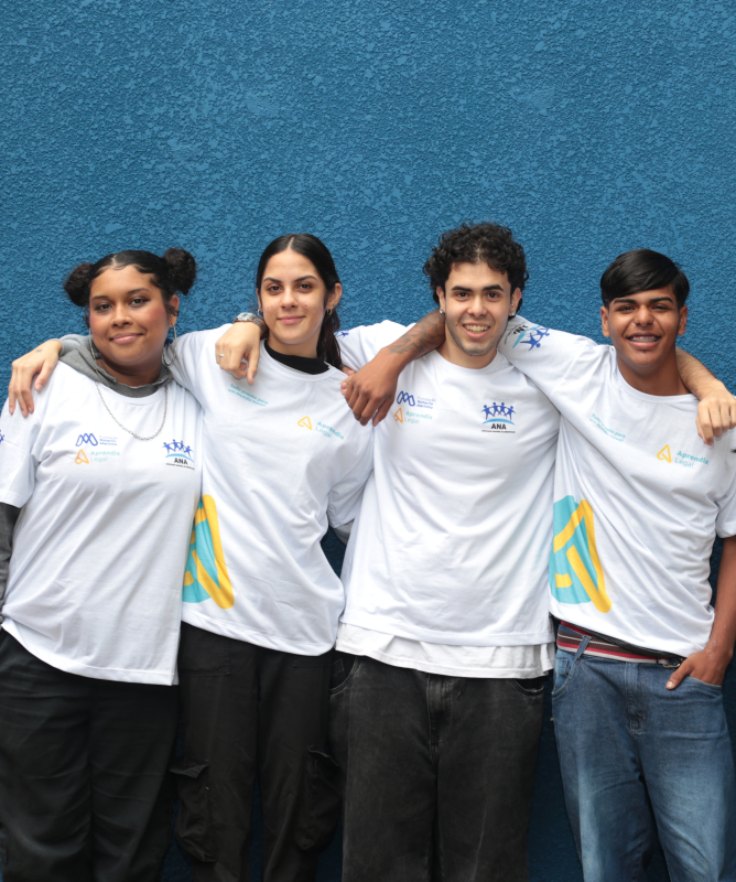 Cinco jovens participantes do Aprendiz Legal posam juntos para uma fotografia. Eles vestem camisetas do programa e aparecem abraçados diante de uma parede azul.