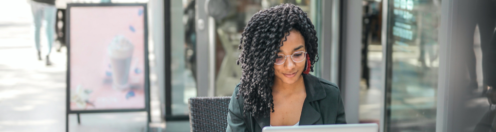 Uma mulher negra está sentada diante de seu laptop.