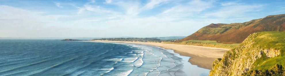 À esquerda, o mar. À direita, praia e montanhas.