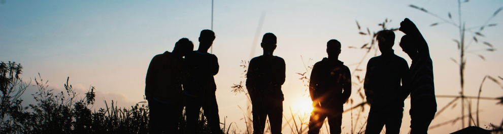 silhuetas de jovens reunidos ao ar livre no entardecer