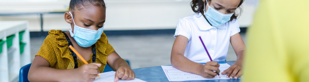 meninas na sala de aula escrevendo e fazendo uso de máscaras de proteção
