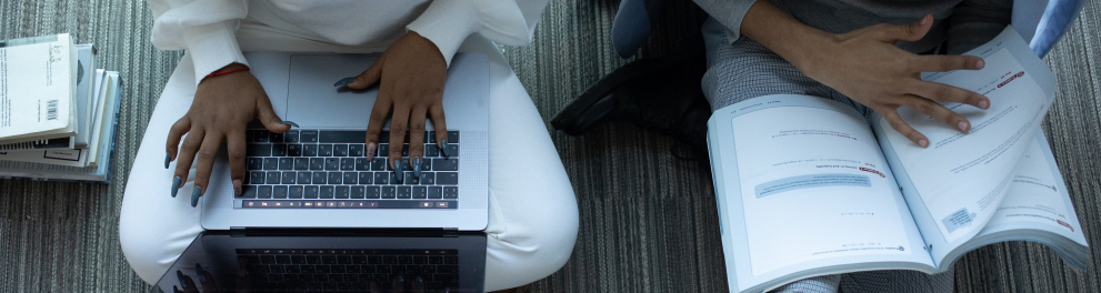 Pessoas usando um laptop e livros podem ser vista de cima