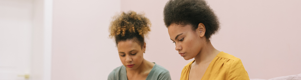 A imagem mostra duas mulheres negras trabalhando em notebooks
