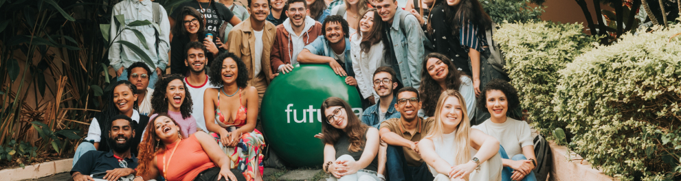 Várias pessoas estão em pé e sentadasao redor da logo do Futura que era uma bola verde com o nome "Futura" escrito em branco dentro dela. Todas e todos estão sorrindo.