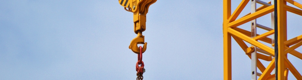Um guindaste amarelo está no centro da imagem. Ao fundo, o céu azul.
