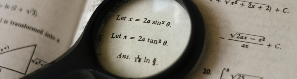 Uma lupa destaca parte de uma equação matemática.