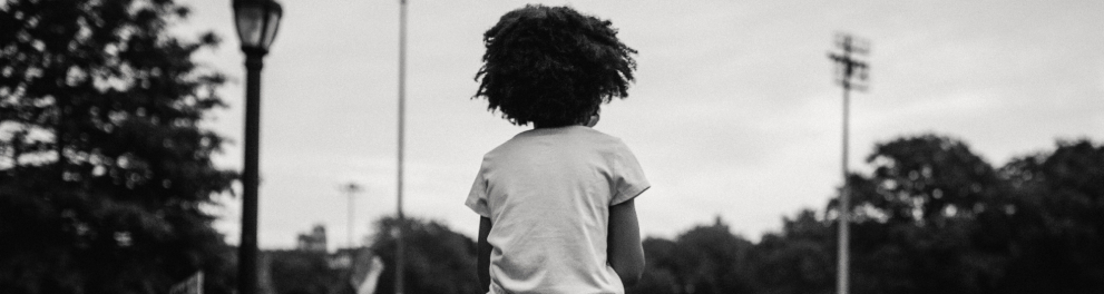 Uma menina netra está no ombro de um adulto, diante de uma multidão.