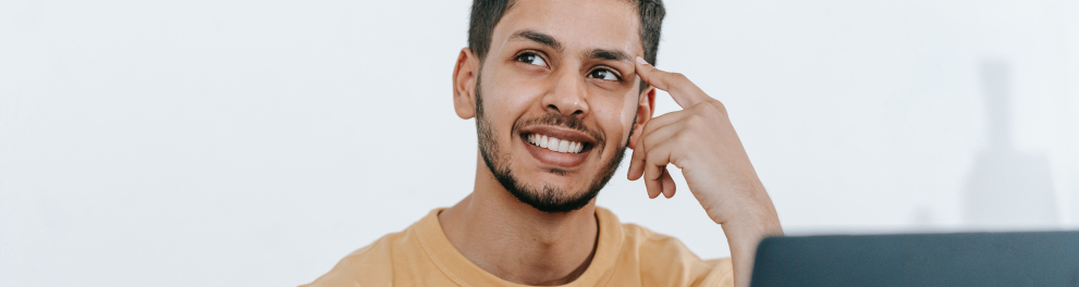 jovem pensando e fazendo anotações com um laptop a sua frente