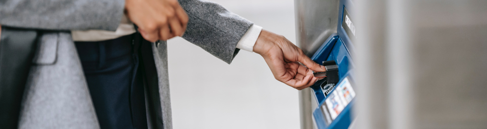 destaque nas mãos de uma pessoa de blazer cinza inserindo um cartão no caixa eletrônicoo