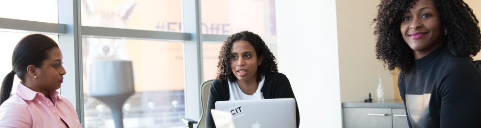 Três mulheres negras em ambiente corporativo