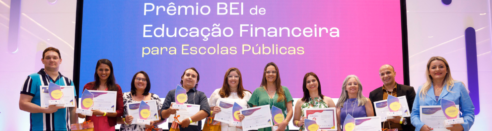 Dez pessoas, entre homens e mulheres, estão de pé em um palco, segurando seus certificados e sorrindo.