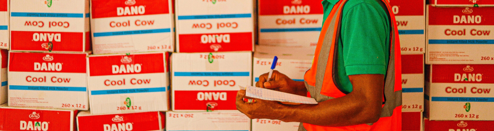 Jovem fazendo anotações conferindo caixas empilhadas no estoque