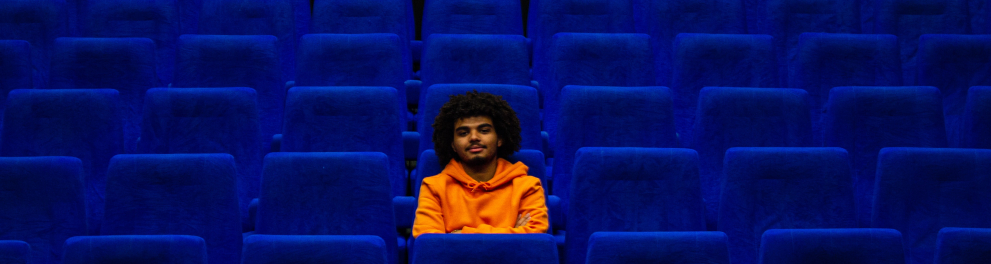 Um homem negro sozinho em uma sala de cinema
