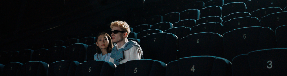 Um casal está sentado, sozinho, em uma sala de cinema.