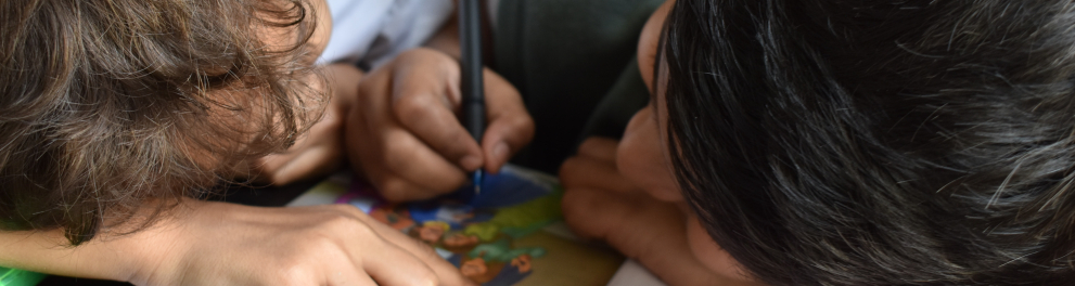 Duas crianças escrevendo em um livro escolar