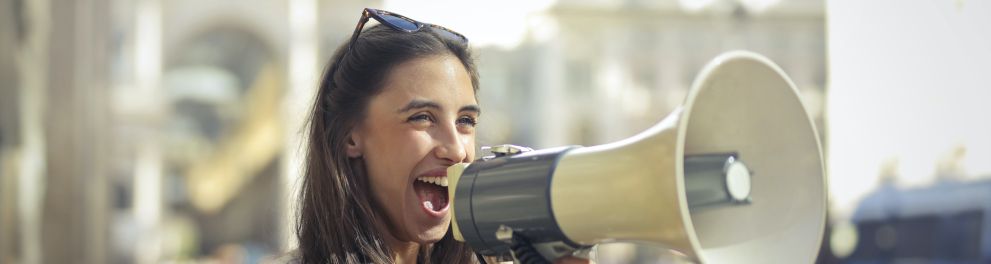 A imagem mostra uma jovem com um megafone em mãos