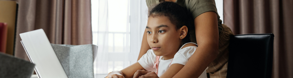 Mão auxiliando a filha a mexer em um notebook