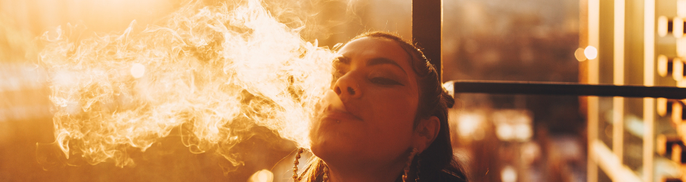 Uma mulher solta fumaça pela boca após fumar um cigarro.