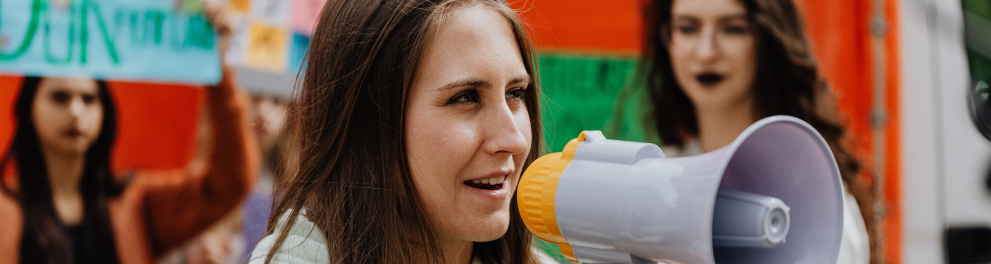Uma mulher branca falando com a ajuda de um megafone