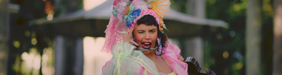 Cantora Anná vestida estilo Carmen Miranda, piscando um dos olhos com um óculos de sol arreado no rosto