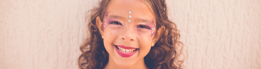 Uma criança com adereços de Carnaval sorrindo para a foto