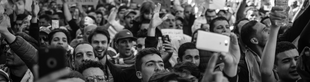 Várias pessoas estão reunidas, manifestando-se sobre algo. A foto é em preto e branco.
