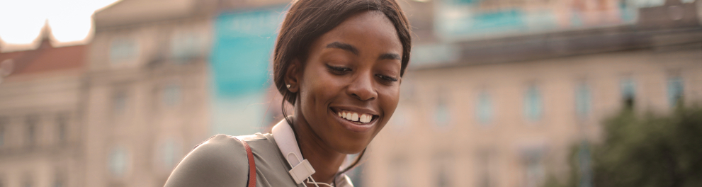 Uma jovem negra sorrindo e olhando para um celular