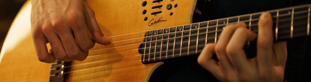 Uma guitarra sendo tocada por um homem que não aparece na imagem, apenas suas mãos