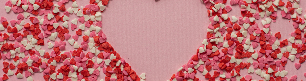 Vários papéis cortados formando corações nas cores branca, vermelha e rosa sobre um fundo totalmente rosa
