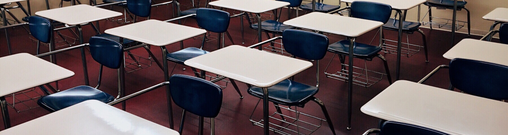 Uma sala de aula vazia de pessoas, apenas com as cadeiras enfileiradas e sozinhas