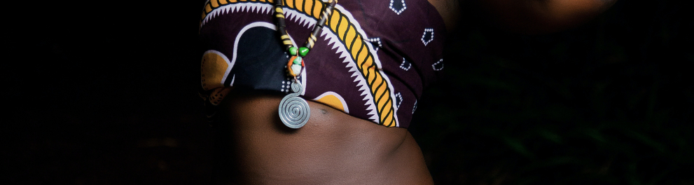 Mulher negra com roupas típicas africanas com as duas mãos no pescoço olhando para cima
