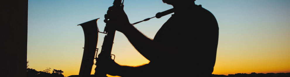 Silhueta de um músico tocando um saxofone ao ar livre