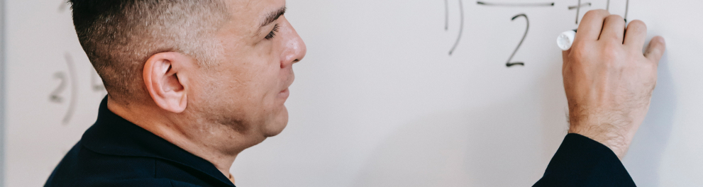 Imagem mostra um Homem escrevendo equação com piloto em quadro branco.