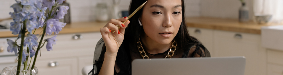 Imagem mostra uma mulher lendo em seu notebook.