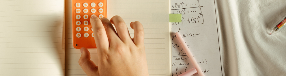 Imagem mostra uma mão sobre calculadora e papel com equações pendendo ao lado.