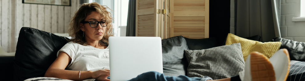 Imagem mostra uma mulher lendo em seu notebook.