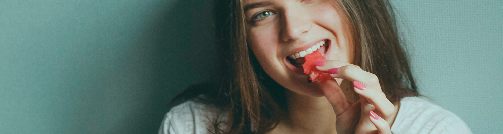 Imagem mostra uma garota comendo melancia.