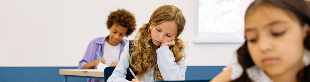 Imagem mostra alunos escrevendo em seus cadernos.