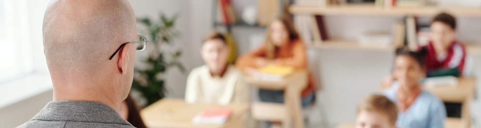 Imagem mostra professor falando com alunos.