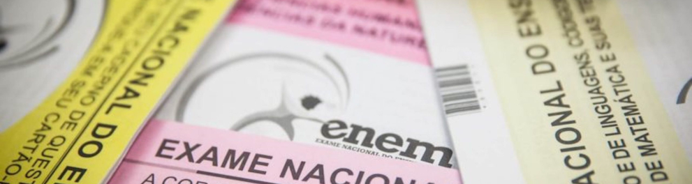 Close em várias provas do ENEM. A imagem mostra uma prova rosa, uma amarela, uma branca e uma azul todas amontoadas uma sobre a outra