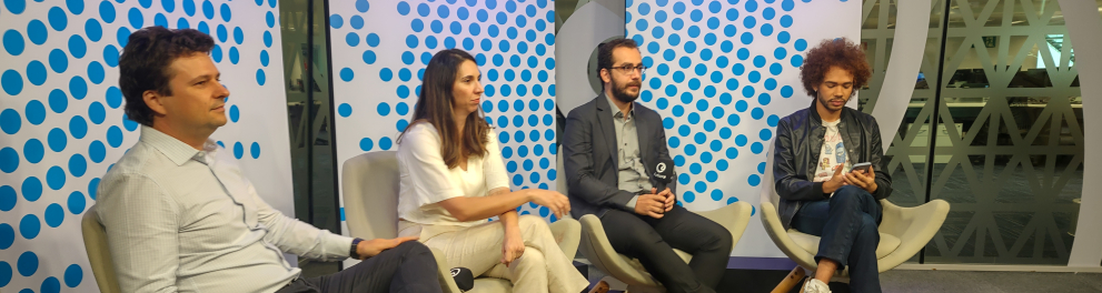 Quatro pessoas estão sentadas em uma sala, lado a lado.